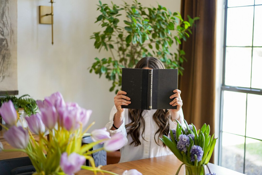 Woman writing in a budget notebook at a kitchen table